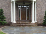 Small patio at front door, flanked by plantings