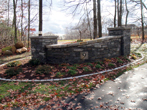 Large stone wall flanking driveway entrance with house number